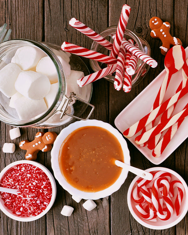Table adorned with bowls of candy canes, marshmallows and sprinkles.